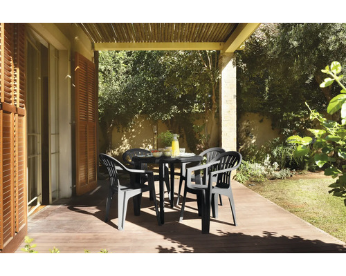 Gartenmöbel-Set mit rundem schwarzem Tisch und vier Kunststoffstühlen auf einer sonnigen Holzterrasse unter einer Pergola im Garten.