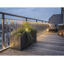 Beleuchtete Dachterrasse mit Holzdeck, Metallgeländer inklusive LED-Streifen, großem Pflanzkübel und Lounge-Möbeln bei Abenddämmerung.