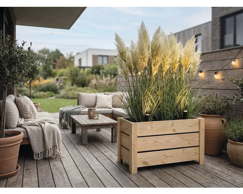 Moderner Terrassenbereich mit großem Holzpflanzkasten mit Pampasgras, Loungemöbeln, Couchtisch und stimmungsvoller Außenbeleuchtung.