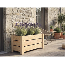 Rechteckiger Pflanzkasten aus Holzlamellen mit blühendem Lavendel auf einer Holzterrasse vor einer Natursteinwand.