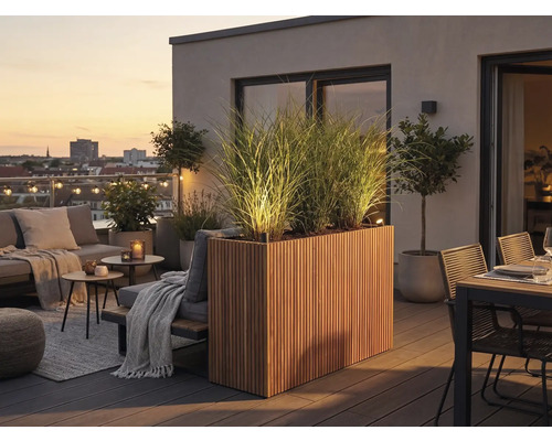 Moderner Dachbalkon mit beleuchtetem Holz-Pflanzkasten, hohen Gräsern, Loungemöbeln und Essbereich auf einer Holzterrasse bei Abenddämmerung.