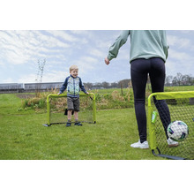 Kind und Erwachsener spielen Fußball im Garten mit zwei kleinen grünen Fußballtoren auf einer Rasenfläche.