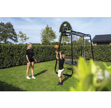 Kind wirft Basketball in Korb an schwarzem EXIT Toys Klettergerüst mit Nestschaukel und Schaukel im Garten.