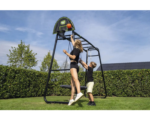 Helles, organisiertes Spielgerät aus Metall mit Basketballkorb, Nestschaukel und Klettergerüst. Frau und Kind spielen. EXIT Toys Logo.