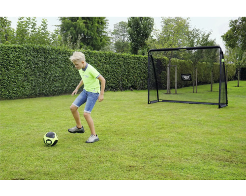 Ein Kind spielt Fußball auf einer Rasenfläche vor einem Fußballtor von EXIT Toys im Garten.