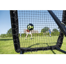 Fußball Rebounder Netz im Garten mit einem fliegenden Fußball und spielenden Personen auf einer Rasenfläche.