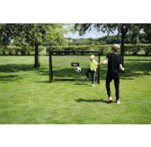 Zwei Kinder spielen Fußball mit einem EXIT Toys Fußballtor auf einer Rasenfläche in einem hellen, sonnigen Garten.