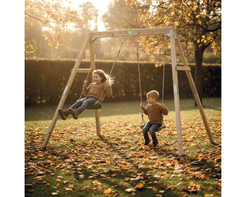 Holz-Doppelschaukel mit zwei schaukelnden Kindern in einem hellen Garten mit herbstlichem Laub.