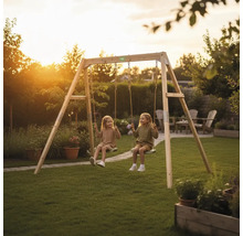 EXIT Toys Doppelschaukel aus Holz im Garten mit zwei spielenden Kindern bei Sonnenuntergang.