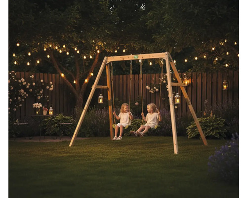 Holzschaukel Set in einem Garten am Abend mit Lichterketten und zwei Kindern auf den Schaukeln.