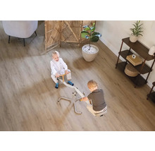 Zwei Kinder spielen auf einer Wippe in einem hellen Zimmer mit einem Bodenbelag in Holzoptik.