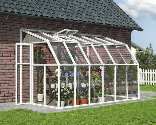 Anlehngewächshaus mit weißem Aluminiumrahmen und Glaspaneelen an einer Ziegelwand, mit verschiedenen Topfpflanzen und Blumen im Inneren.