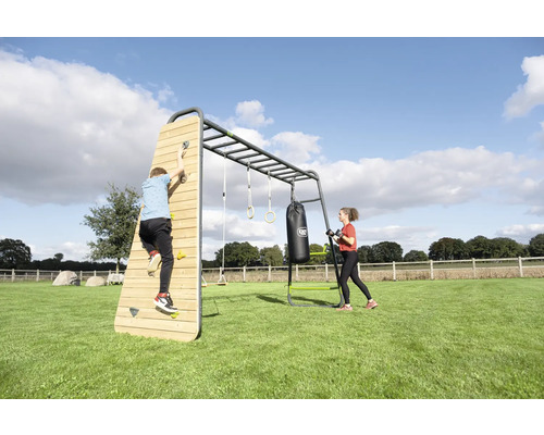 Großes Outdoor-Fitness- und Klettergerüst mit Kletterwand aus Holz, Hangelstangen, Turnringen und Boxsack auf einer Rasenfläche.