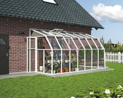 Helles, weißes Anlehn-Gewächshaus aus Aluminium und Glas an einer Ziegelwand mit Dachfenster und organisierten Pflanzen in einem Garten.