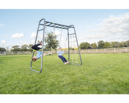 Klettergerüst aus Metall mit Schaukel, Kletternetz und Turnringen im Garten mit spielenden Kindern.