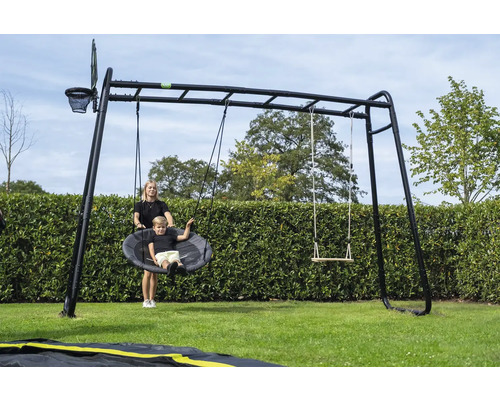 Schwarzes Garten-Klettergerüst mit Nestschaukel, klassischer Schaukel, Monkey Bar und Basketballkorb auf einer Rasenfläche mit Hecke.