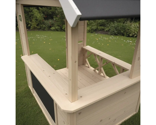 Spielhaus aus Holz in Kiosk-Optik mit Verkaufstresen und Kreidetafel auf einer Rasenfläche.