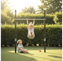 Kinder spielen an einem freistehenden Turnreck aus Metall in einem hellen Garten vor einer Hecke.