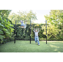 Zwei Kinder spielen an einer Doppel-Reckstange aus Metall im Garten auf einer Rasenfläche.