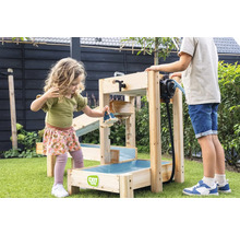 Kinder spielen im Garten mit einer EXIT Toys Wasserbahn aus Holz, ausgestattet mit einer Wasserpumpe und mehreren Ebenen auf grünem Rasen.