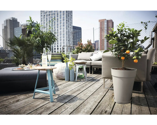 Dachterrasse mit Holzdiele, grauem Loungesofa, Pflanzkübel mit Zitrusbaum, blauem Beistelltisch und Blick auf die Stadt.