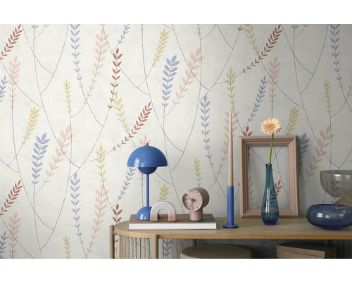 Mustertapete mit feinen Zweigen und bunten Blättern hinter einem Konsolentisch mit Lampe, Vase und weiteren Dekoobjekten.