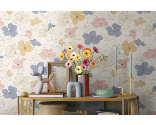 Vliestapete mit großflächigem Blumenmuster in Pastelltönen an einer Wand hinter einer dekorierten Konsole.