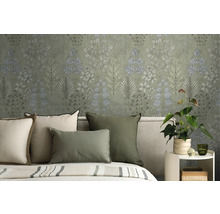 Vliestapete mit botanischem Blättermuster im Schlafzimmer hinter einem Bett mit grünen und cremefarbenen Kissen.