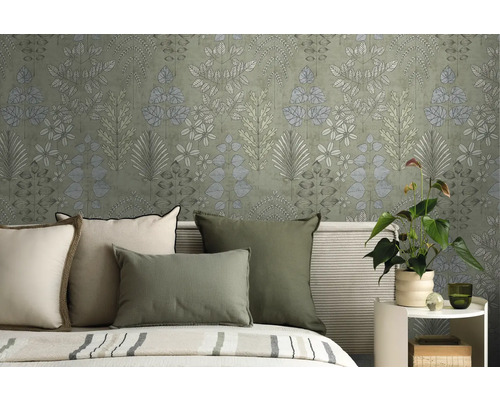 Vliestapete mit botanischem Blättermuster im Schlafzimmer hinter einem Bett mit grünen und cremefarbenen Kissen.