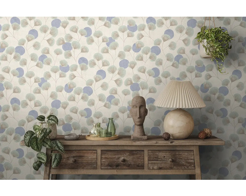 Tapete mit Ginkgoblatt- und Kreismuster hinter einer rustikalen Holzkommode mit Steinfigur, Glasflaschen, Pflanzen und einer Tischleuchte.