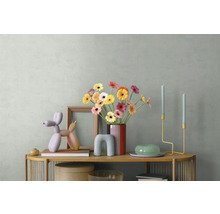 Moderne Sideboard-Dekoration mit bunten Gerbera in einer Vase, einer Ballonhund-Skulptur, Holzrahmen und minimalistischen Kerzenhaltern.