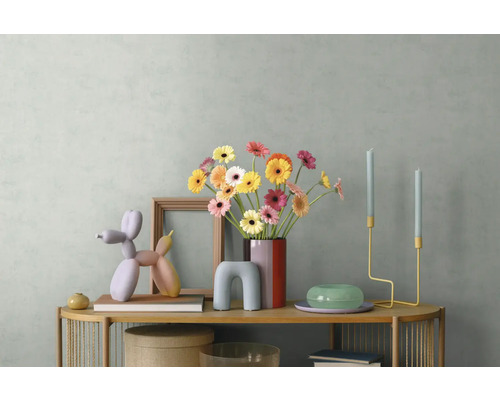 Moderne Sideboard-Dekoration mit bunten Gerbera in einer Vase, einer Ballonhund-Skulptur, Holzrahmen und minimalistischen Kerzenhaltern.