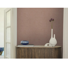 Strukturierte Vliestapete in Altrosa auf einer Wand hinter einem Holzsideboard mit Lamellen, einer weißen Vase und einer blauen Glasschale.