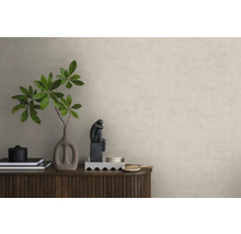 Vliestapete in Putzoptik an einer Wand hinter einem Sideboard aus Holz mit Dekoration wie einer Vase mit Zweigen und einer Skulptur.