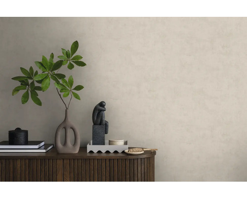 Vliestapete in Putzoptik an einer Wand hinter einem Sideboard aus Holz mit Dekoration wie einer Vase mit Zweigen und einer Skulptur.