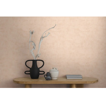 Strukturierte Vliestapete an einer Wand in einem modern eingerichteten Raum mit einem Holztisch, einer Vase mit Zweig, Keramik und Büchern.