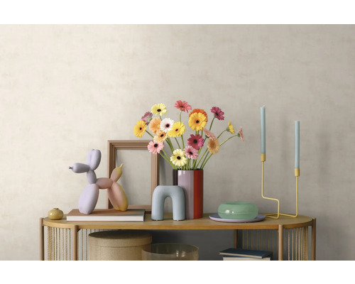 Moderne Inneneinrichtung mit Holz-Sideboard, buntem Gerbera-Strauß, Ballonhund-Skulptur, Kerzenständern und Bilderrahmen vor heller Wand.
