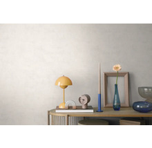 Helles, organisiertes Arrangement auf einem Holz-Sideboard vor einer strukturierten, hellen Wand mit einer gelben Tischlampe, Uhr und Blumenvase.