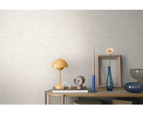 Helles, organisiertes Arrangement auf einem Holz-Sideboard vor einer strukturierten, hellen Wand mit einer gelben Tischlampe, Uhr und Blumenvase.