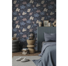 Vliestapete mit großflächigem Blumenmuster in einem modern eingerichteten Schlafzimmer mit grauem Bett und dekorativem Beistelltisch.