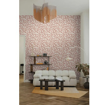 Vliestapete mit rosa Blattmuster in einem modern eingerichteten Wohnzimmer mit weißem Sofa und dunklem Couchtisch.