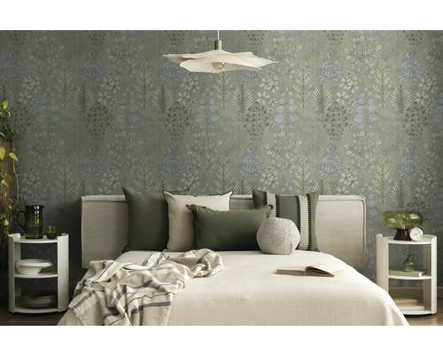 Helles Schlafzimmer mit botanischer Mustertapete, Bett mit Stoffkopfteil, grünen und beigen Kissen sowie weißen runden Nachttischen.