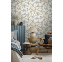 Vliestapete mit Ginkgoblatt-Motiv und Kreisen in einem hellen Zimmer mit Holzmöbeln, Tischlampe und Bett.