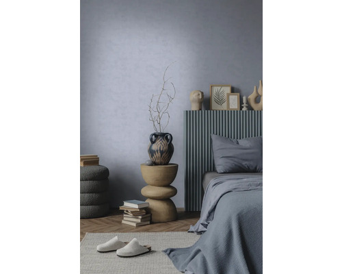 Modernes Schlafzimmer mit hellblau strukturierter Wand, Bett mit grauem Lamellen-Kopfteil und skulpturalem Beistelltisch aus Holz.