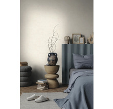 Helle, strukturierte Wand in einem minimalistischen Schlafzimmer mit grauem Bett, Holzbeistelltisch und Parkettboden im Fischgrätmuster.
