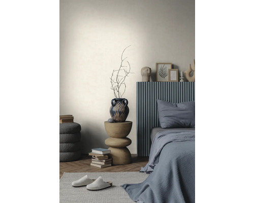 Helle, strukturierte Wand in einem minimalistischen Schlafzimmer mit grauem Bett, Holzbeistelltisch und Parkettboden im Fischgrätmuster.