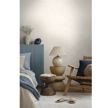 Modernes Schlafzimmer mit einem Holzstuhl, einem skulpturalen Beistelltisch aus Holz, einer Tischlampe mit Plisseeschirm und einem Bett mit blauem Paneel.