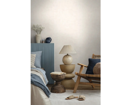Modernes Schlafzimmer mit einem Holzstuhl, einem skulpturalen Beistelltisch aus Holz, einer Tischlampe mit Plisseeschirm und einem Bett mit blauem Paneel.