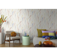 Vliestapete mit filigranem Blättermuster in einem hellen Wohnzimmer mit modernem Sessel, Sofa und Beistelltisch.