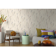 Vliestapete mit botanischem Blattmuster in einem hellen Wohnzimmer mit Sessel und Sofa.